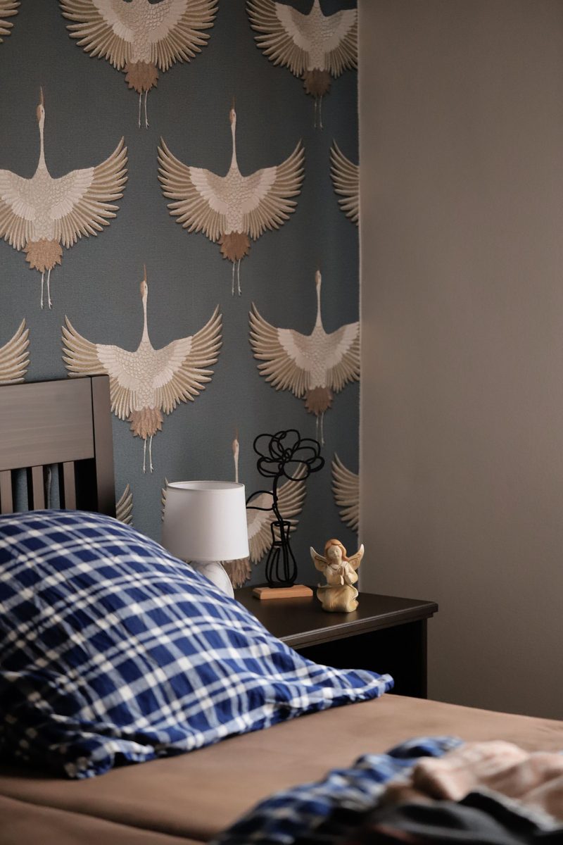 Bedroom with a navy wallpaper featuring pale crane and bird motifs