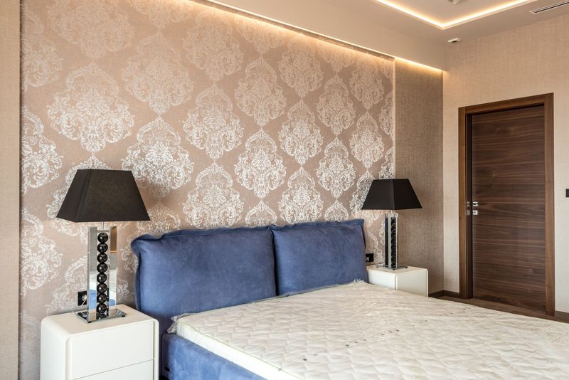 Bedroom with a cream damask wallcovering and blue velvet headboard