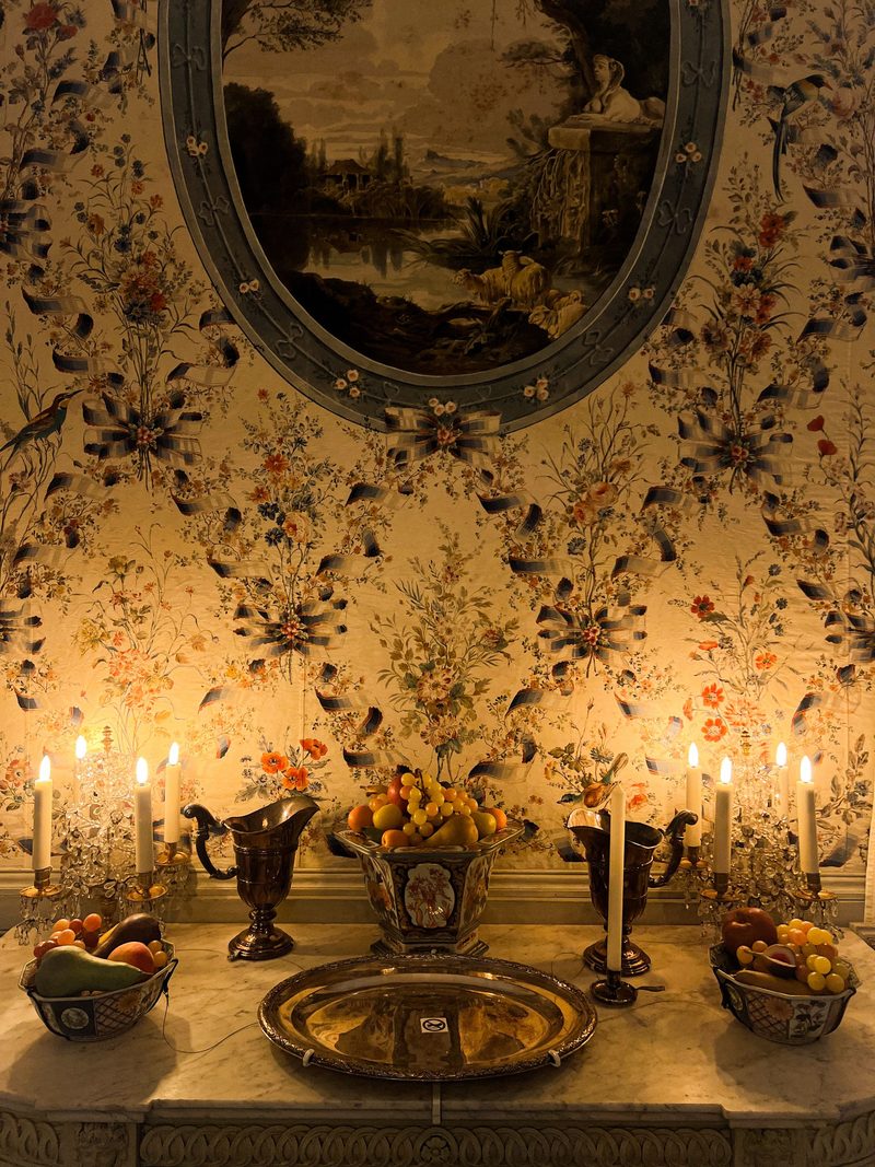 Dark floral chinoiserie wall with candlelight and a console table