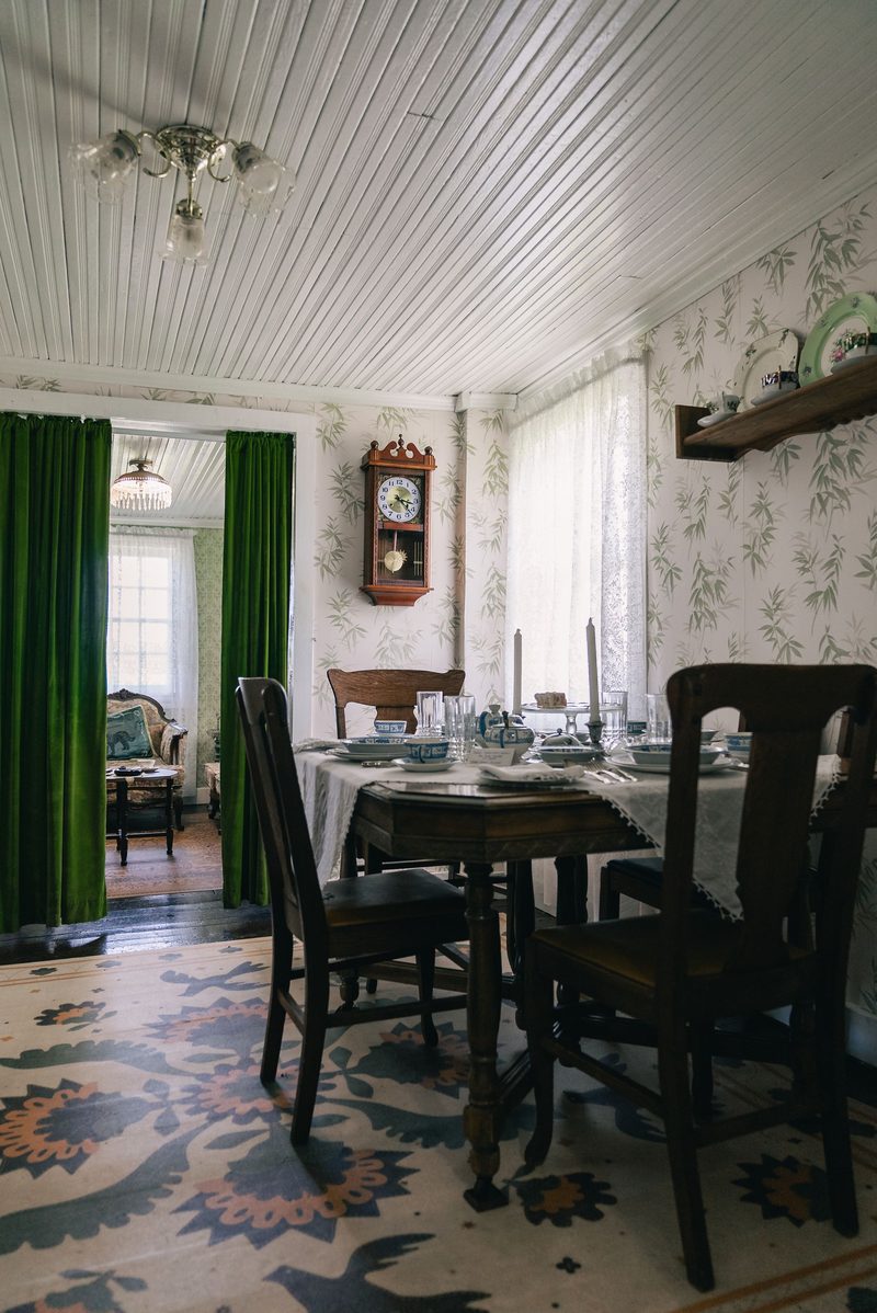 Traditional dining room with patterned walls and green drapes