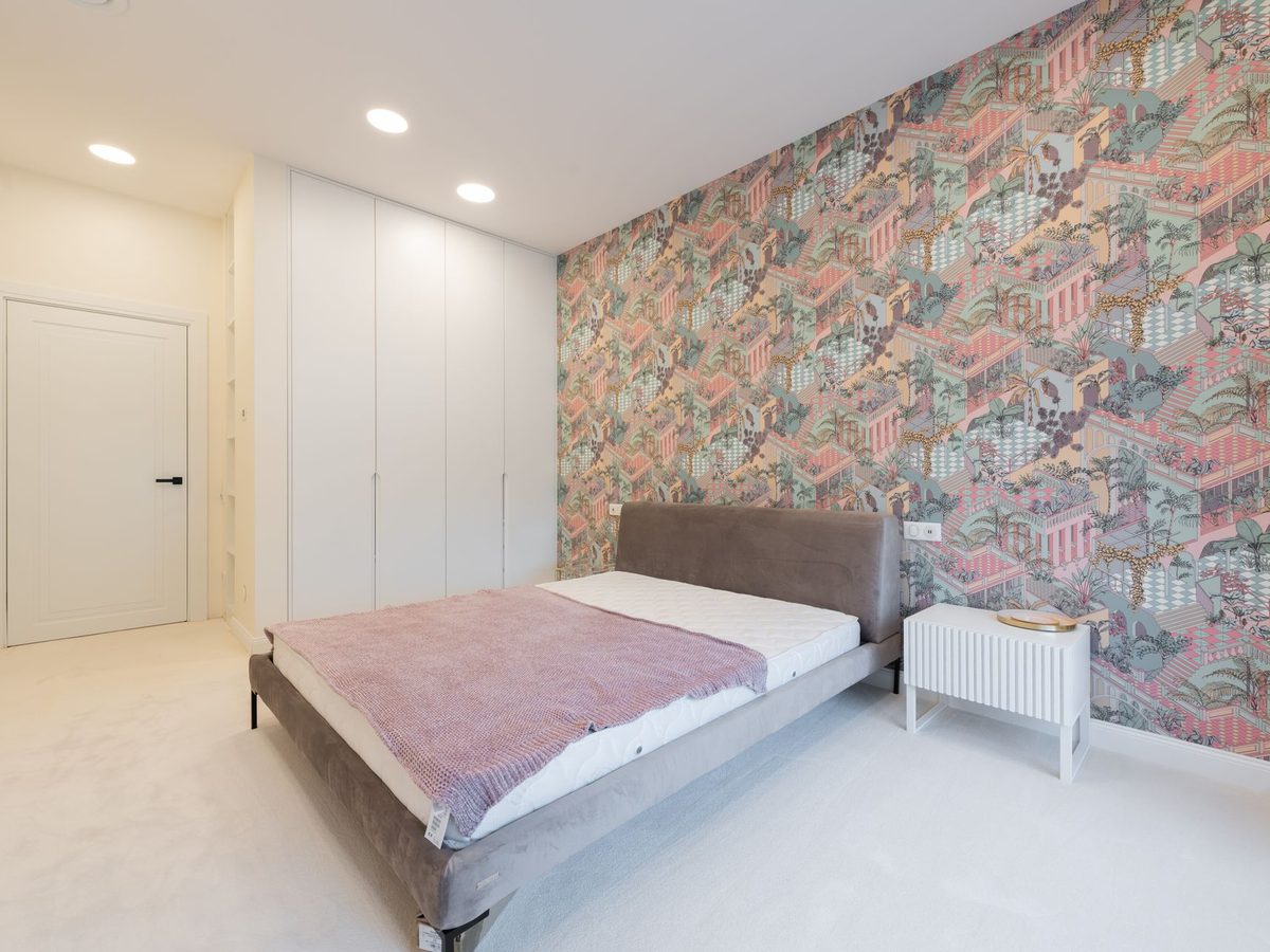 Bright modern bedroom with a colorful patterned feature wall behind the bed